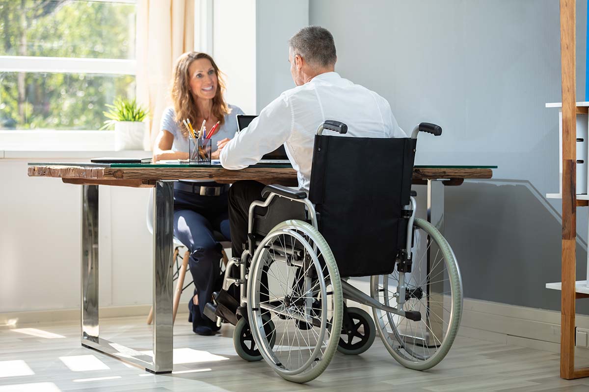 Why-Occupational-Therapists-are-Ideal-for-Home-Assessments Man in wheelchair sitting at table meeting with a therapist